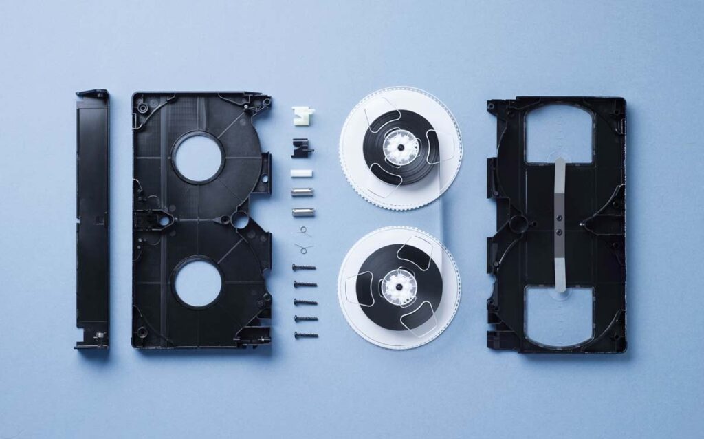 Unveiling the Inner Workings: Disassembled VHS Tape Spread Out on a Captivating Blue Background