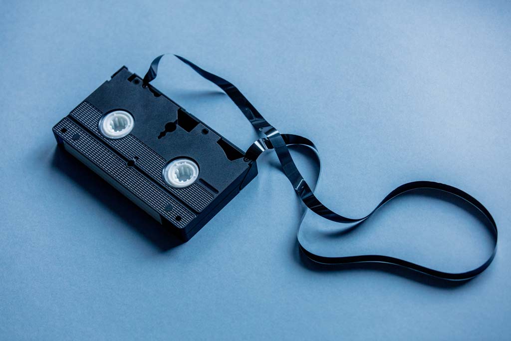 Unleash Nostalgia: VHS Tape Spewing Memories on a Vibrant Blue Canvas